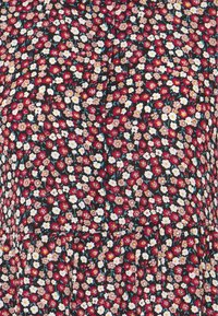 Motif floral dense sur tissu avec de petites fleurs rouges, blanches et roses et des feuilles vertes sur fond noir.