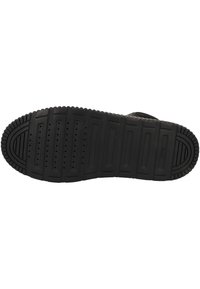 Semelle de chaussure en caoutchouc noir avec un motif de semelle comprenant des rainures, des crêtes et des perforations pour l'adhérence et la flexibilité. Texture lisse dans l'ensemble.