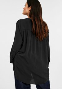 Mustavartalo-pitkähiha_blouse, jossa on löysä malli, laskostettu selkäosa ja pyöreä kaula-aukko, valmistettu kevyestä ja sileästä kankaasta.