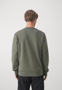 Maglione verde oliva, vestibilità standard, collo a giro, polsini e orlo a coste, realizzato in materiale morbido, vista posteriore che mostra una texture liscia.