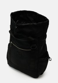 Mochila negra tipo roll-top fabricada en nylon duradero, con un bolsillo frontal con cremallera, correas ajustables y bolsillos de malla laterales para almacenamiento.