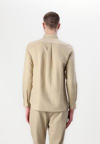 Lichtbeige lange mouw blouse van linnen, met een achterzijde yoke, knoopmanchetten en een ontspannen pasvorm, gecombineerd met bijpassende broek.