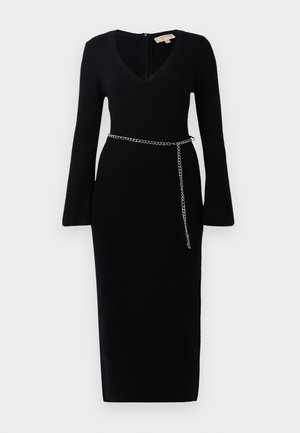 Black ribbed long-sleeve midi dress with V-neck and flared cuffs, featuring a slim silver chain belt around the waist.