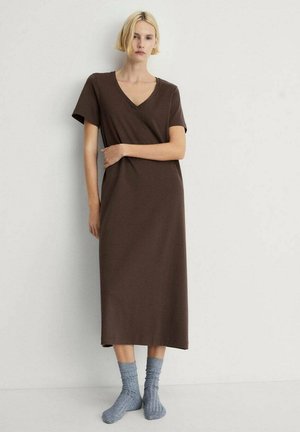 Abito maxi marrone a maniche corte con scollatura a V. Tessuto morbido, vestibilità rilassata e silhouette dritta. Abbinato a calzini azzurri chiari con texture.