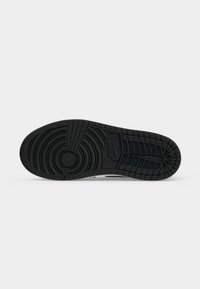 Σόλα μαύρου αθλητικού παπουτσιού Nike που δείχνει κυκλικά, γραμμικά και πλέγμα μοτίβα στο πέλμα με το λογότυπο της Nike στην περιοχή του μέσου ποδιού.