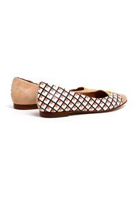 Zapatos de ballet con un talón de ante beige y una parte superior blanca con un patrón de cuadrícula en negro y rojo, suela plana y diseño de punta redondeada.