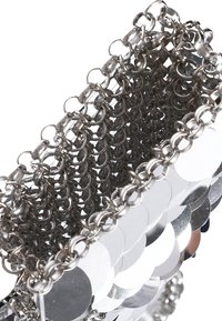 Metalická řetízková kabelka s kulatými flitry ve stříbrné barvě, s tkaným designem. Hladký povrch s reflexními plochami a spojenými kroužky.