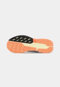 Suela de goma naranja y negra con patrones de agarre texturizados; presenta el logo "NIKE TRAILT" y un acento en crema claro.