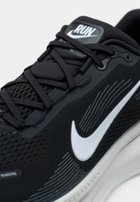 Adidașii negri de alergare cu partea superioară din plasă, swoosh alb și accente texturate. Prezintă șireturi negre și o talpă din cauciuc cu caneluri distincte.
