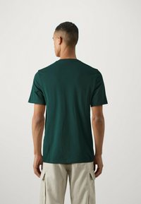 T-shirt verde in cotone con colletto rotondo, maniche corte e vestibilità rilassata. Presenta una texture liscia e un design semplice.