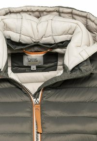 Grijze, gevoerde pufferjack met een label van gerecycled materiaal. Crème-gekleurde binnenkant, oranje ritsaccenten en een capuchon met drukknoopjes.