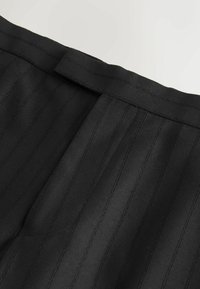 Black pinstriped fabric featuring a smooth texture and structured seams. The waistband is neatly finished with a flat design.