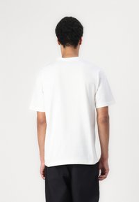 Hvid bomulds T-shirt med korte ærmer og rund hals. Har en afslappet pasform og ensartet tekstur uden synlige mønstre eller grafikker.