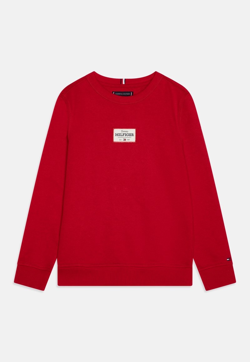 Sweatshirt rouge à manches longues, col rond et poignets côtelés. Présente une patch logo rectangulaire sur le devant avec le nom de la marque.