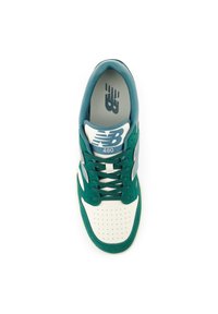 Grön och krämfärgad sneaker med ovandel i läder och mocka, perforerad tåruta, vita snören och en logo på tungan.