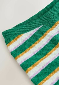 Gros plan d’un tissu tricoté vert avec des rayures diagonales blanches, jaune moutarde et violet clair, et une taille côtelée.