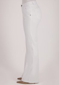 Witte flared jeans met een gladde textuur, met voor- en achterzakken en metalen knoopaccenten, weergegeven vanuit een zijaanzicht.