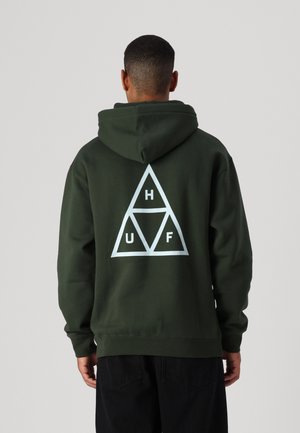 Sudadera verde oscura con un gran logo triangular blanco en la parte posterior, que presenta las letras "H", "U" y "F" dentro de los triángulos. Textura de tela suave.