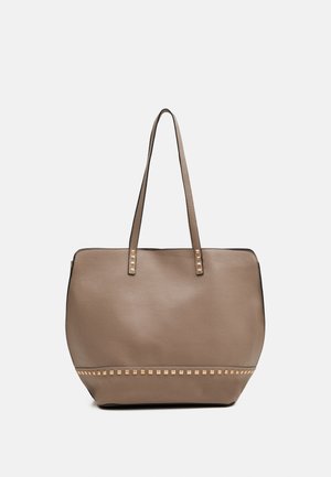 Sac fourre-tout en cuir taupe avec deux fines bretelles et une rangée de petits clous carrés dorés le long du bord inférieur et à la base des bretelles.