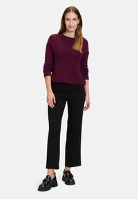 Pull en tricot bordeaux avec ourlet côtelé, associé à un pantalon noir ajusté et des chaussures noires imposantes. Design simple et coupe décontractée.