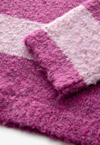 Filztextil aus Wolle in lebhaftem Pink mit einem helleren rosa Streifen. Besitzt eine strukturierte, flauschige Oberfläche und ein geschichtetes Design.