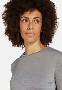 Hellgraues Kurzarmshirt mit rundem Ausschnitt, das aus einem strukturierten Stoff besteht und einen lässigen Schnitt hat. Ein subtiler Glanz sorgt für visuelles Interesse.
