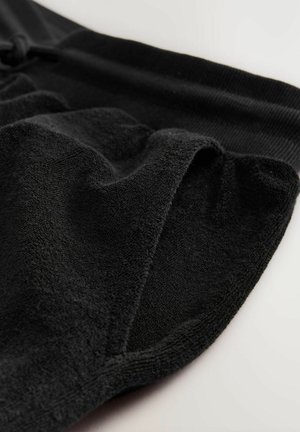 Sorte shorts lavet af blødt, tekstureret stof med snoretræk i taljen og et afslappet design, der har en glat overflade og diskrete sydetaljer.