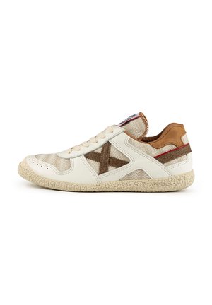 Zapatilla blanca con un upper texturizado de color beige y acentos marrones, además de un diseño tejido. Suela de goma natural con un acabado pattern.