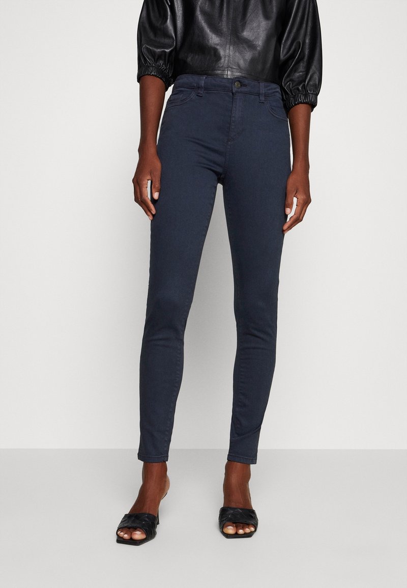 Jean skinny bleu foncé en denim, avec un design classique à 5 poches, une fermeture à boutons à l'avant et des détails de coutures discrètes.