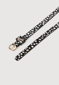 Schwarz-weißer gepunkteter Gürtel mit einer goldenen Schnalle, der eine weiche Textur und ein Lederfinish aufweist. Das Muster besteht aus unregelmäßigen weißen Punkten.