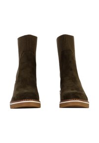 Botas de tobillo de ante marrón con parte superior de punto acanalado, punta en forma de almendra y costuras blancas contrastantes en la suela beige.