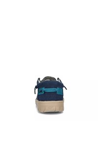 Scarpa di tela blu con superficie testurizzata, dotata di una fascia accentuata color teal e suola in gomma crema. La vista posteriore mostra i passanti per i lacci e un design flessibile.