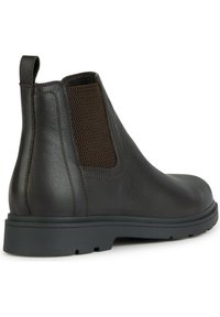Botas de tobillo de cuero marrón con un panel lateral elástico texturizado, suela de goma plana y una lengüeta en la parte posterior para facilitar el uso.