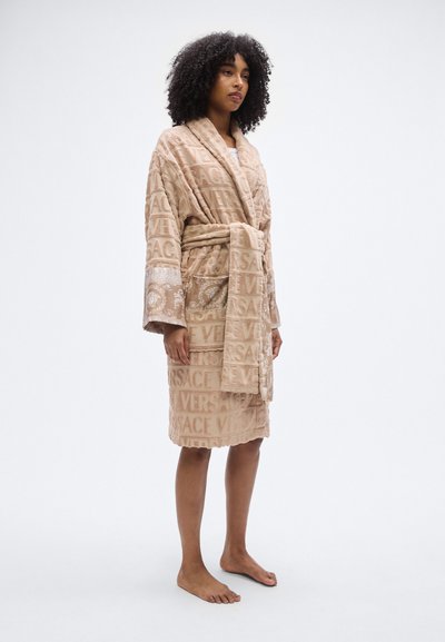 Μπεζ μπουρνούζι από περκάλι με ανάγλυφο μοτίβο λογότυπου "VERSACE", ζώνη στη μέση και φαρδιά μανίκια. Διακοσμητικές λεπτομέρειες στα μανίκια.