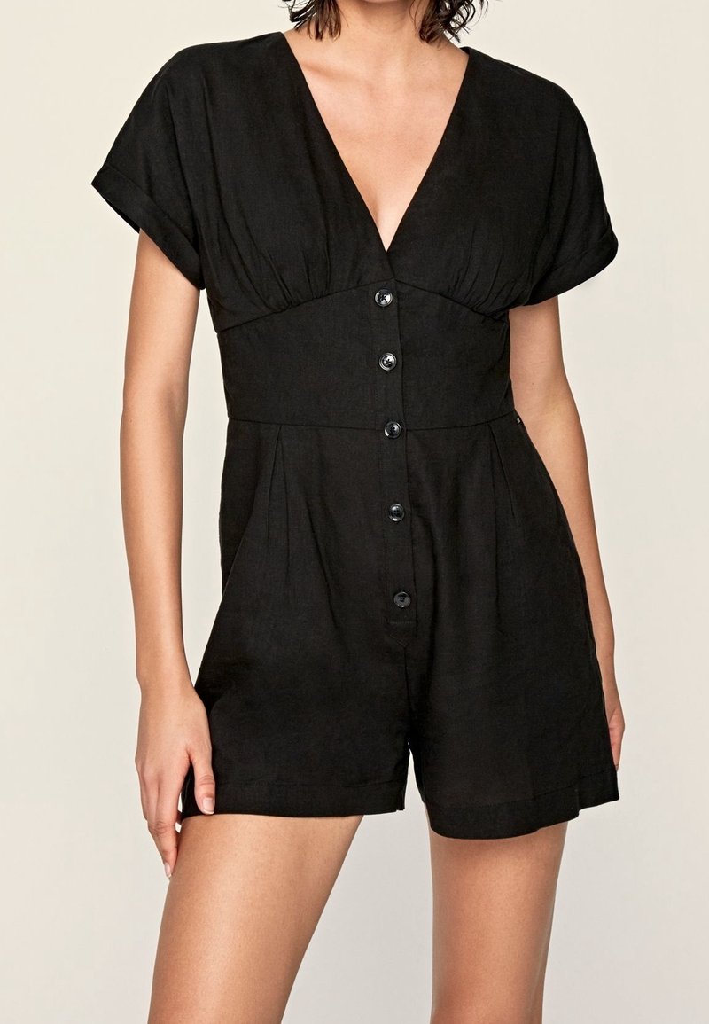 Czarny leniany kombinezon z krótkimi rękawami, głębokim dekoltem w kształcie V, zapięciem na guziki z przodu oraz kieszeniami po bokach. Gładka faktura i luźny fason.
