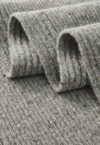 Grå ribbad tyg med en texturerad yta, som visar veck och subtila flerdolkar för extra detalj. Mjukt ulligt material.