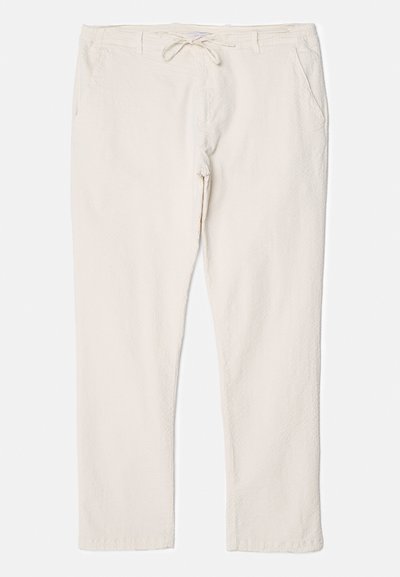 Light beige trousers with a textured surface, elastic waistband, and adjustable drawstring, featuring two side pockets for storage.