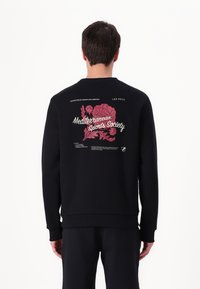 Black sweatshirt featuring a floral graphic and text on the back, round neckline, ribbed cuffs and hem, made from soft fabric.