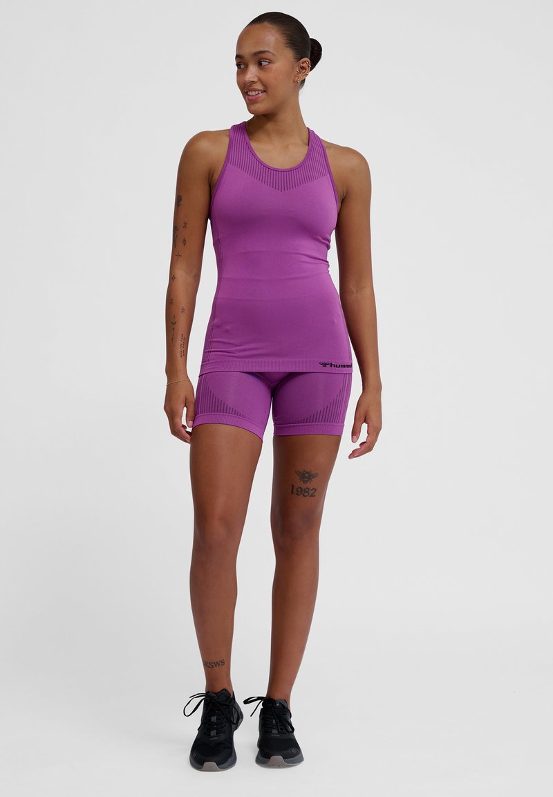 Purple athletic tank top and shorts set with ribbed texture, form-fitting design, and logo on the waistband, paired with black sneakers.