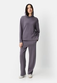 Kaptrui met lange mouwen en wijde broekspijpen in gedempt paars, gemaakt van zachte stof met een gladde textuur en subtiele stikseldetails.