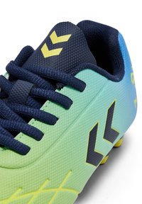 Chaussure de football vert citron et bleu foncé avec dessus texturé, lacets bleu marine, accents jaunes et logo triangulaire sur la languette.