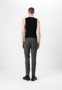 Svart ärmlös topp kombinerad med grå skräddarsydda byxor, med en smal passform, slät textur och kompletterad med svarta skor.