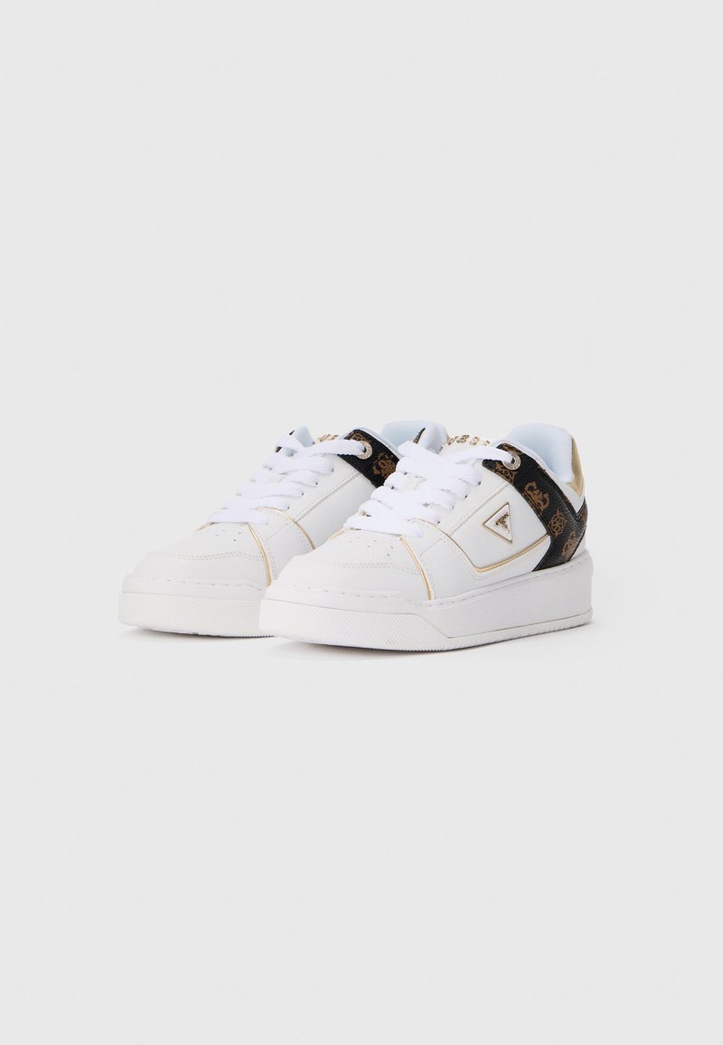 Witte lage sneakers met witte veters, zwart en bruin patroon op de hiel, en een driehoekig metalen logo aan de zijkant.