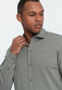 Helle graue Button-up-Hemd aus Baumwollmischung mit einem strukturierten Kragen, langen Ärmeln und einem kleinen gestickten Logo auf der Brust.