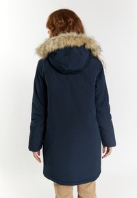 Parka albastră închis cu glugă și margine din blană artificială. Prezintă o croială dreaptă, mâneci lungi și o textură netedă, potrivită pentru îmbrăcămintea de iarnă.