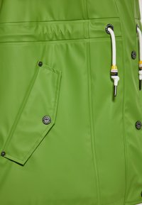 Šviesiai žalia vandeniui atspari striukė su blizgiu paviršiumi, turinti kišenę su užklotu, reguliuojamą kapušoną ir kontrastingus metalinius akcentus.