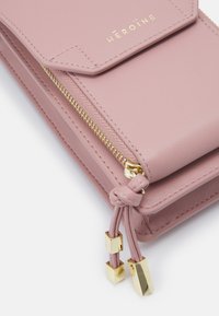 Portafoglio in pelle rosa chiaro con finiture dorate, dotato di chiusura con zip, superficie texturizzata e una placca con logo sulla parte frontale.