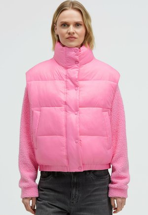 Rosa Steppweste mit hohem Kragen, ausgestattet mit Knopfverschluss und Fronttaschen. Die Ärmel sind mit flauschigem pinkem Stoff bedeckt.