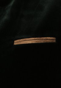 Schwarzsamte Stoff mit einem schmalen, horizontalen braunen Reißverschlussakzent, der prominent in der Mitte dargestellt ist.