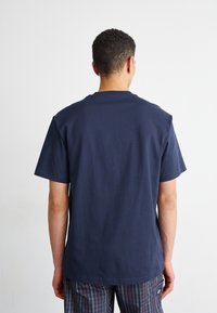 Marineblå crewneck t-shirt lavet af bomuld, med korte ærmer og en afslappet pasform. Glat tekstur uden synlige mønstre eller accenter.